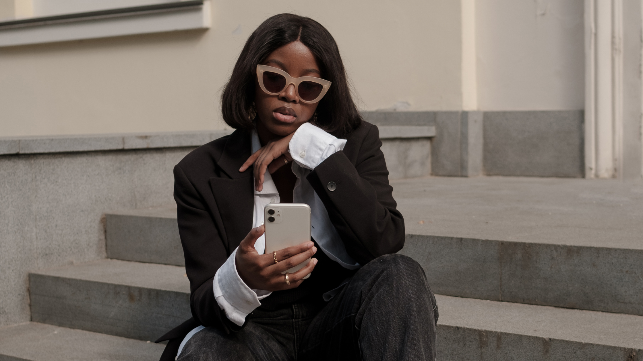 Black women influencer sitting in a staircase looking at his key metrics Influencer looking at his metrics to analyze the Return on Investment (ROI) for a new campaign she did for a company